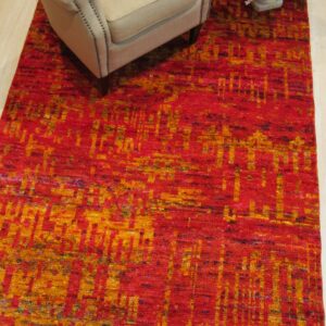 Red sari-silk Anand rug styled in a room with an armchair