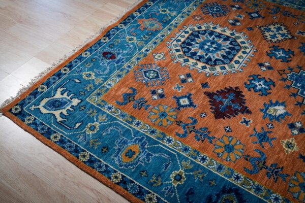 Rust blue kazak rug corner and blue border detail