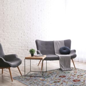 Dahlia Oriental Gray Hand Knotted Wool Rug displayed on a polished hardwood floor with delicate floral motifs in shades of gray and cream