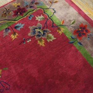 Corner of a red Chinese Art Deco carpet with a dark branch bearing red and blue blossoms and a butterfly above the taupe border