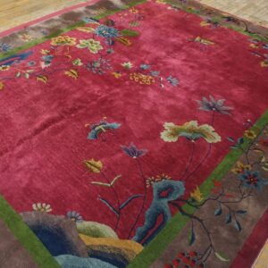 Angled corner of a red 1920s Chinese Art Deco rug on wood flooring, with blue rockwork and teal and cream florals
