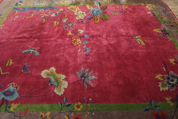 Antique red color classic chinese art deco design room size carpet 4 Upper corner of a red chinese art deco rug with gold and cream blossoms and blue-grey leaves meeting the green frame and taupe border