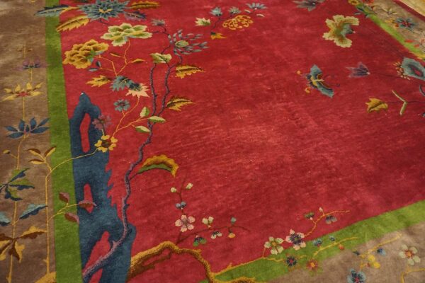 Antique red color classic chinese art deco design room size carpet 6 Angled detail of a red chinese art deco rug showing a blue rockwork column and gold and olive florals inside the green inner frame