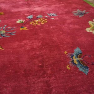 Field detail of a red Chinese Art Deco rug with a blue butterfly, cream and olive blossoms and a gold chrysanthemum