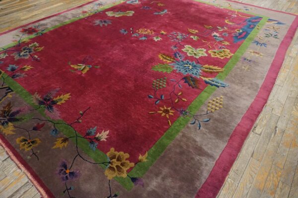 Antique red color classic chinese art deco design room size carpet 9 Angled full view of a red chinese art deco room size rug on plank flooring, showing the green frame and taupe outer border