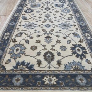 Close up of the ivory field and slate blue floral border on the Charming Oushak hand knotted wool runner rug