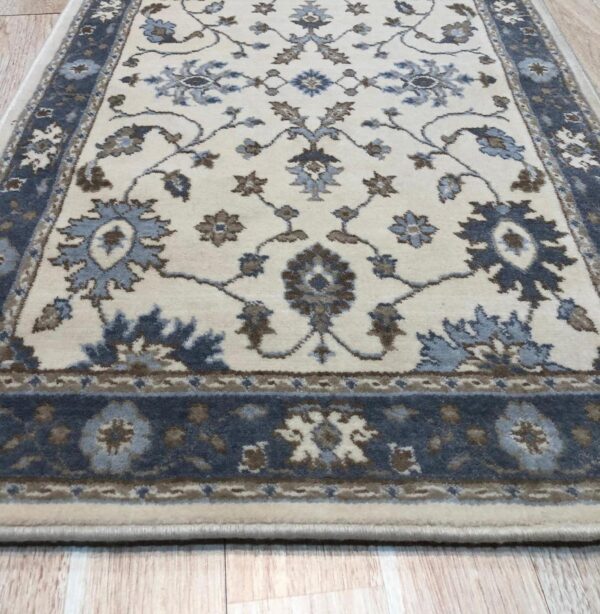 Detail of the blue, brown and cream palmette and vine pattern on the charming oushak ivory wool runner rug