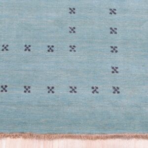Close up of the aqua rug pile with charcoal four dot cross motifs and blush fringe.