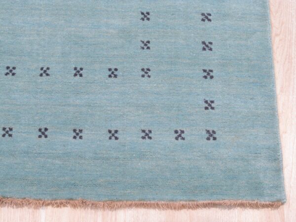 Jasmine alluring aqua handmade wool rug 3 Close up of the aqua rug pile with charcoal four dot cross motifs and blush fringe.