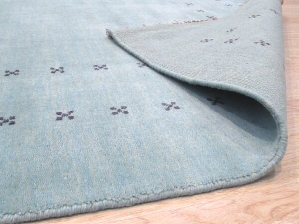 Jasmine alluring aqua handmade wool rug 2 Corner of the aqua wool rug folded back to show the hand knotted foundation and low even pile.