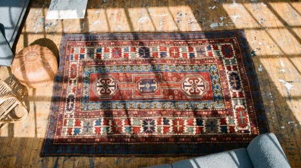 Antique red caucasian tribal geometric medallion kazak rug 2 Antique red caucasian tribal geometric medallion kazak rug (sku 19575) - styled overhead view