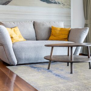 Steel blue and gray abstract hand knotted wool rug in a living room under a sofa and coffee table
